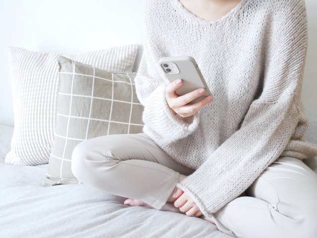 A‐woman‐holding‐a‐smartphone‐in‐her‐loungewear